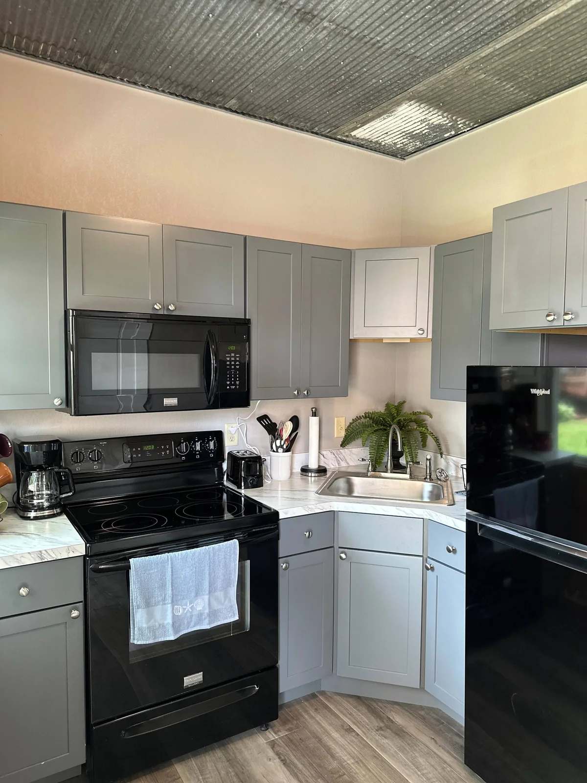 Actual kitchen with gray cabinets, stove and refrigerator