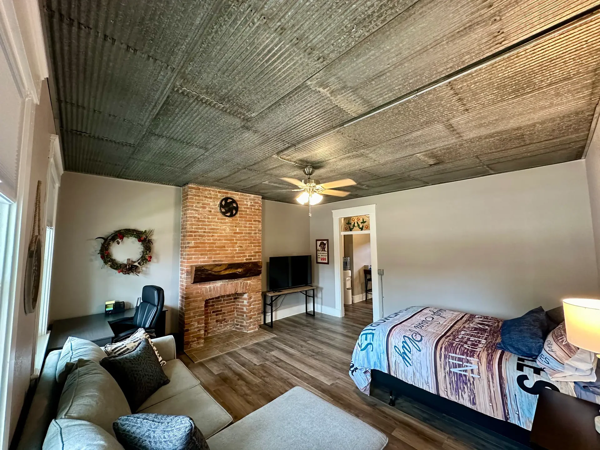 Open-plan bedroom and seating area, with brick feature and tin ceiling
